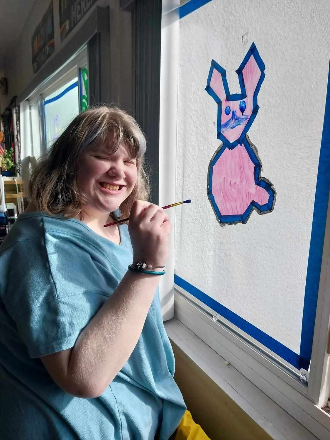 Resident painting a colorful rabbit on the window.