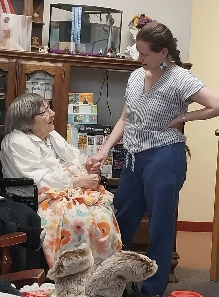 Senior resident interacting with staff member in a cozy setting.