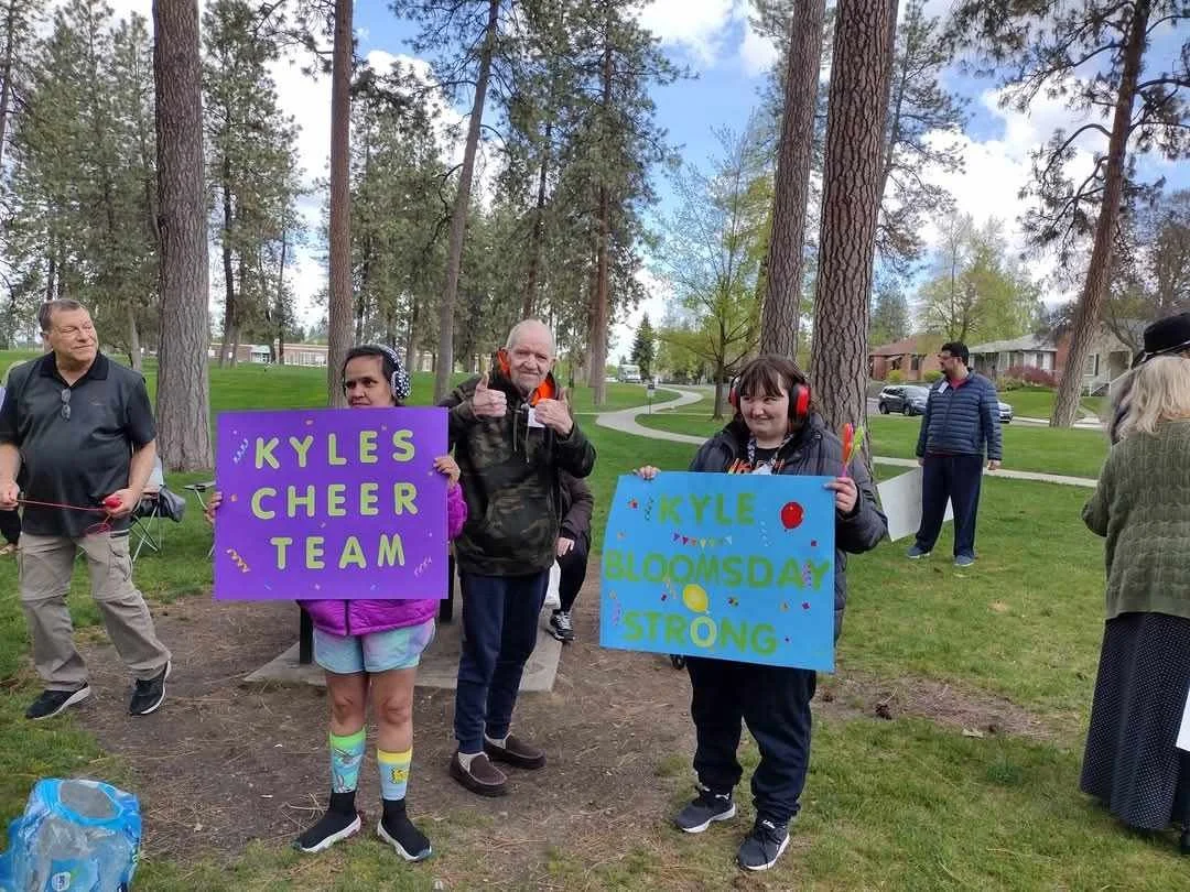 Residents holding colorful signs at an outdoor event.