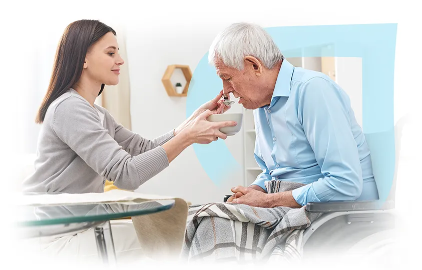 A caregiver feeding a senior resident in a comfortable setting.