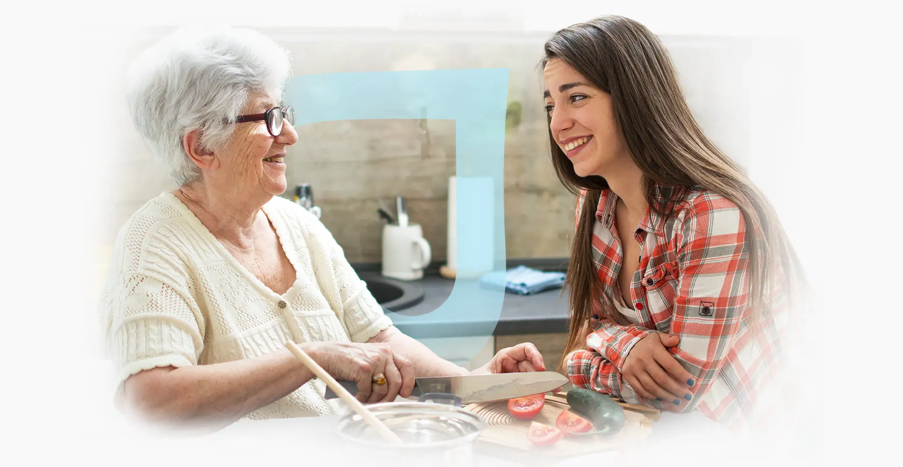 Elderly woman and caregiver laughing while preparing food.