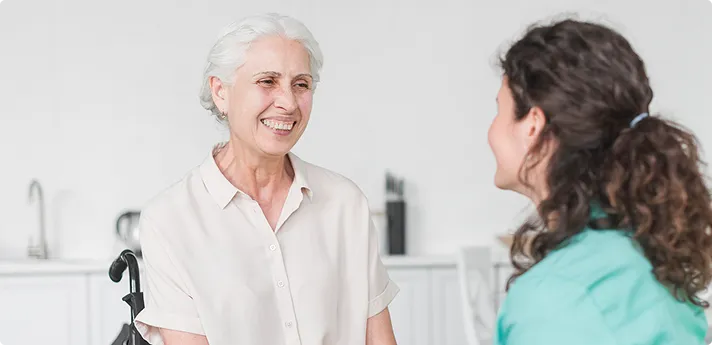 Senior woman smiling with caregiver in conversation