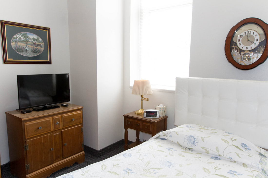 Cozy resident room with bed, TV, and furniture