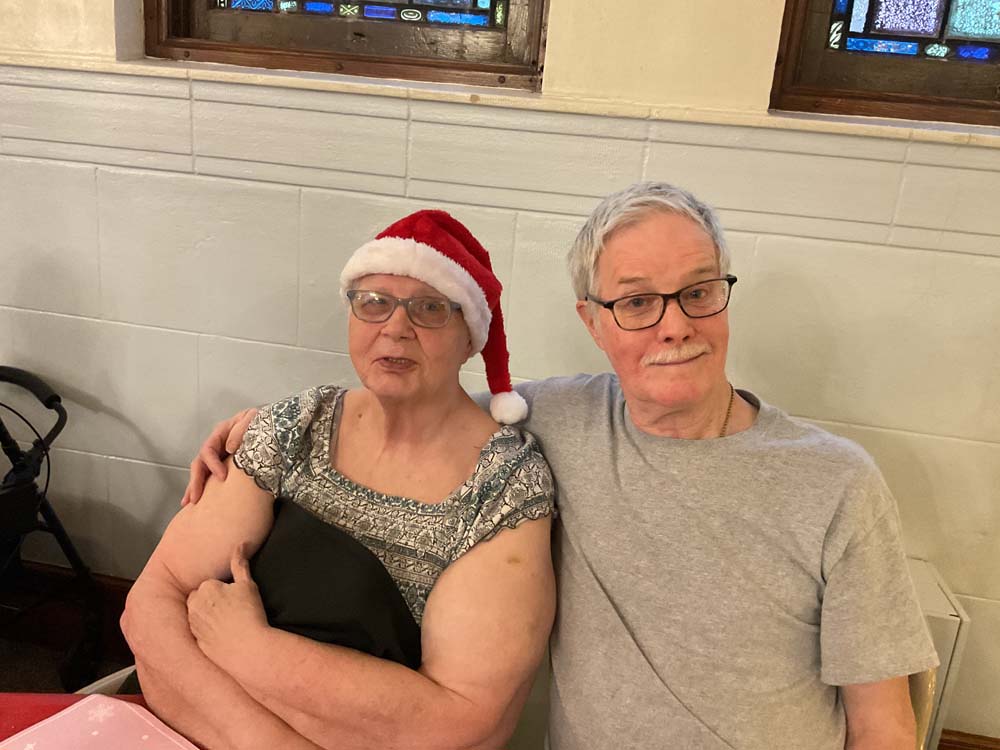 Two residents sharing a moment, one in a Santa hat