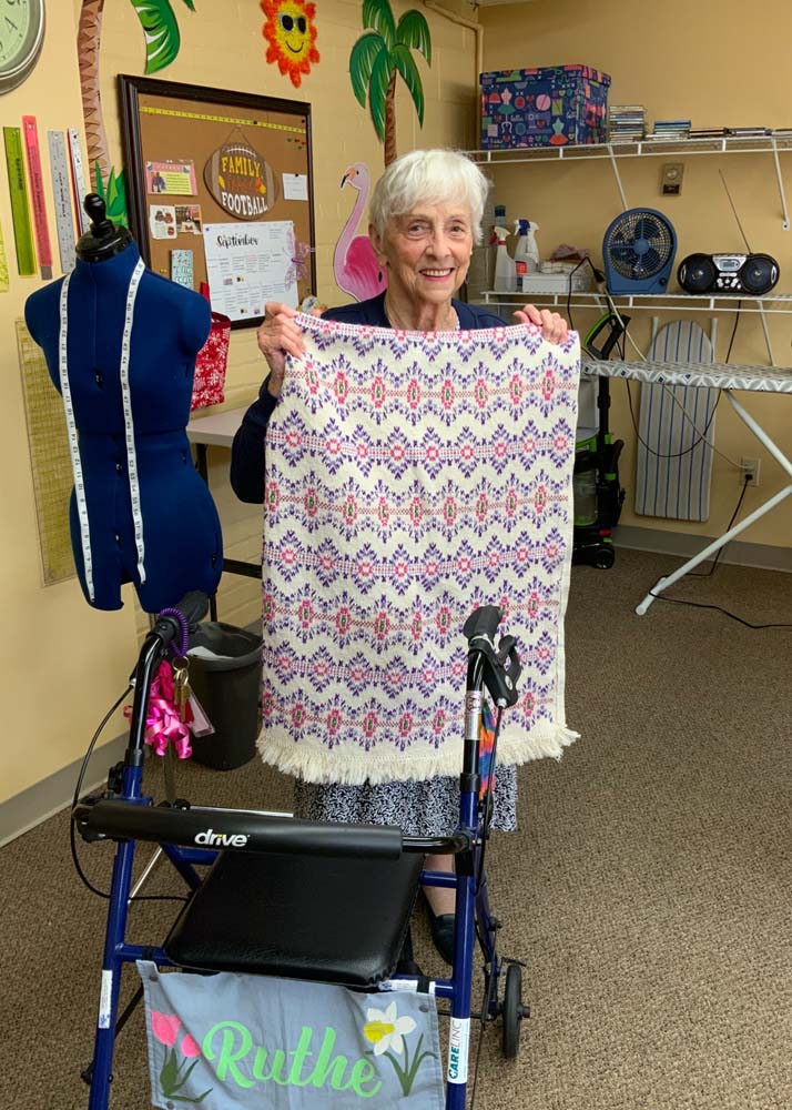 A resident showing a handmade blanket in an activity room
