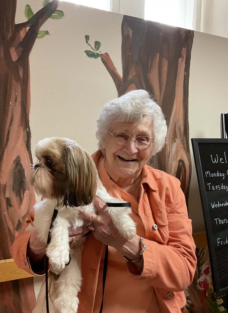 Elderly woman holding a small dog, smiling