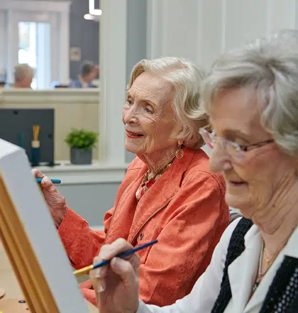 Two residents painting in an activity room