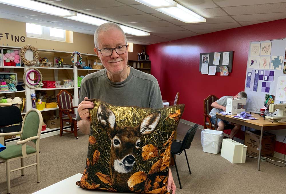 Resident holding a decorative pillow in a craft room