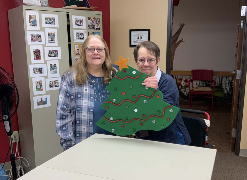 Two residents proudly display a handmade Christmas tree decoration