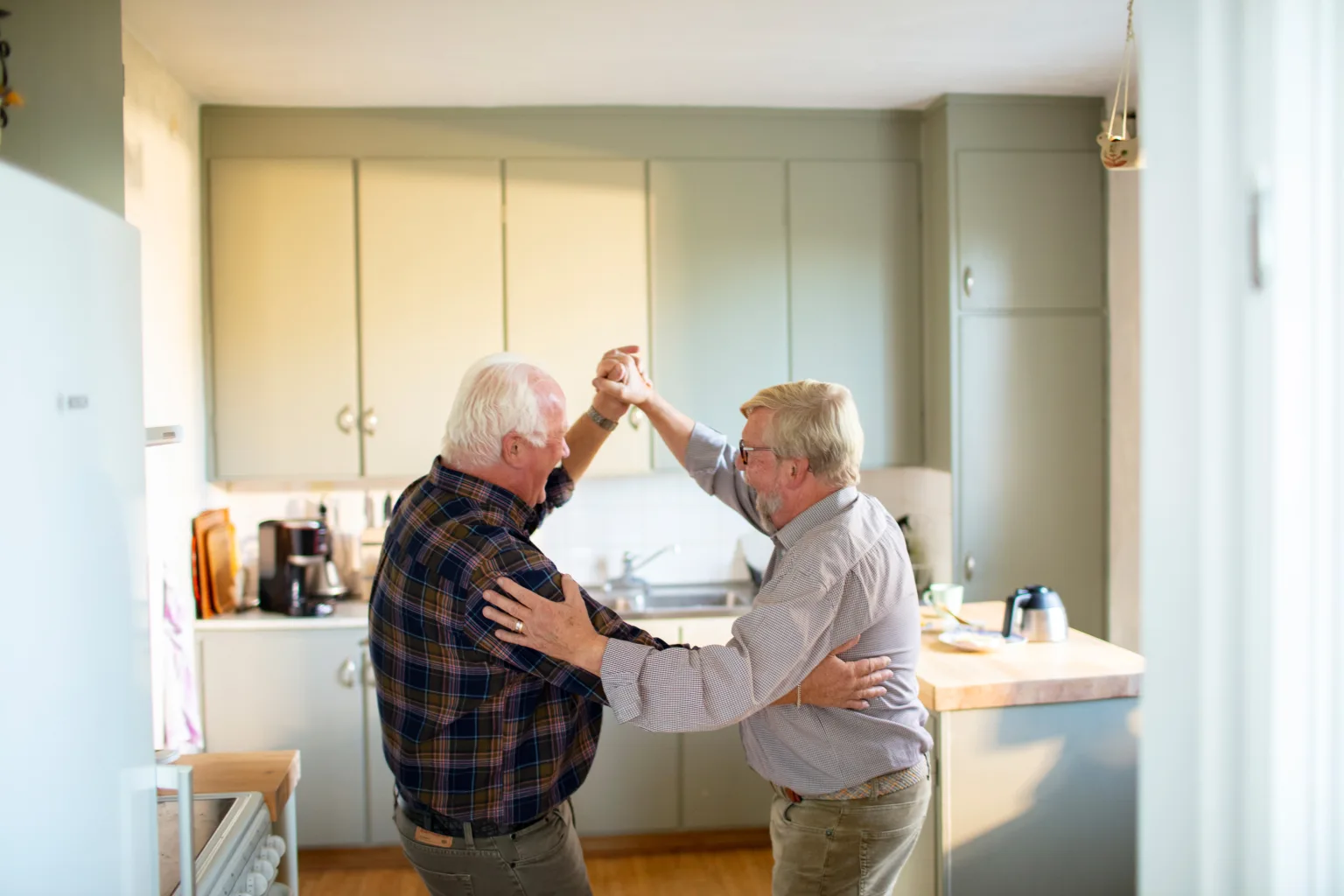 Two residents dancing in a cozy kitchen.
