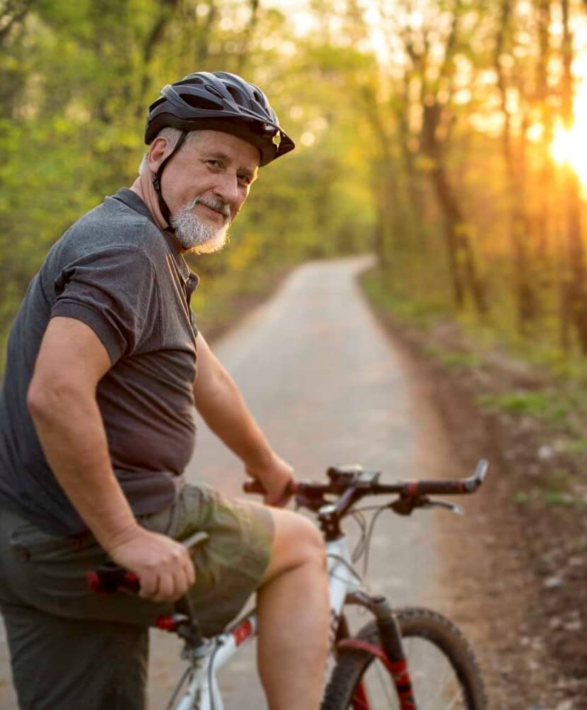 A senior man cycling on a path in a scenic outdoor area