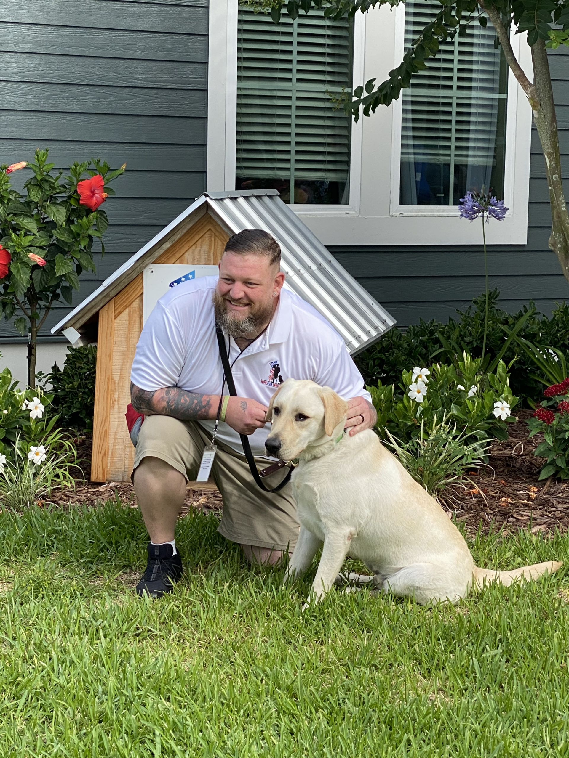 A staff member with a dog in a garden area