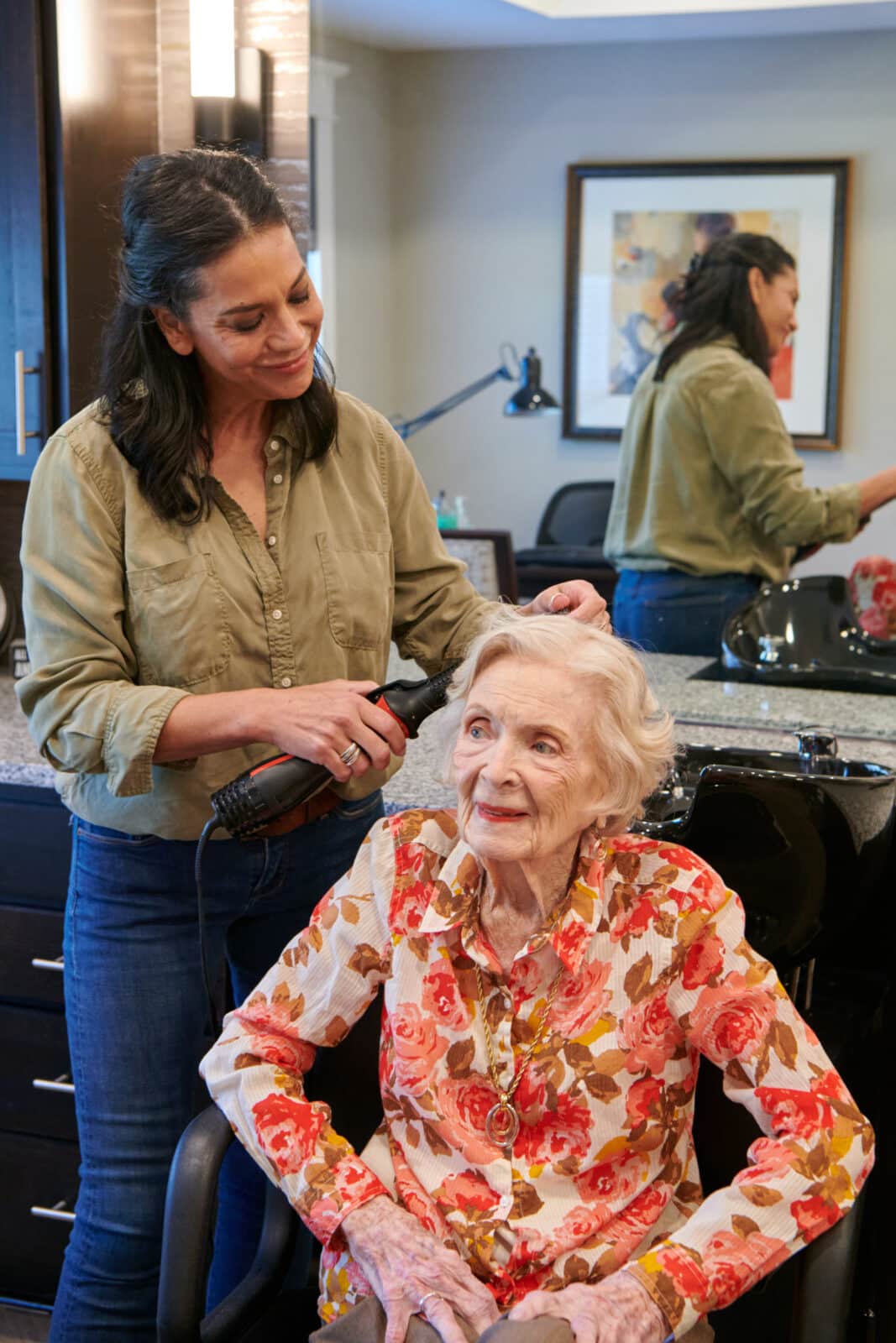 A staff member doing a resident's hair in a salon setting