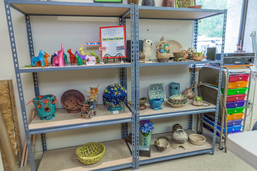 Shelves displaying handcrafted pottery and art pieces