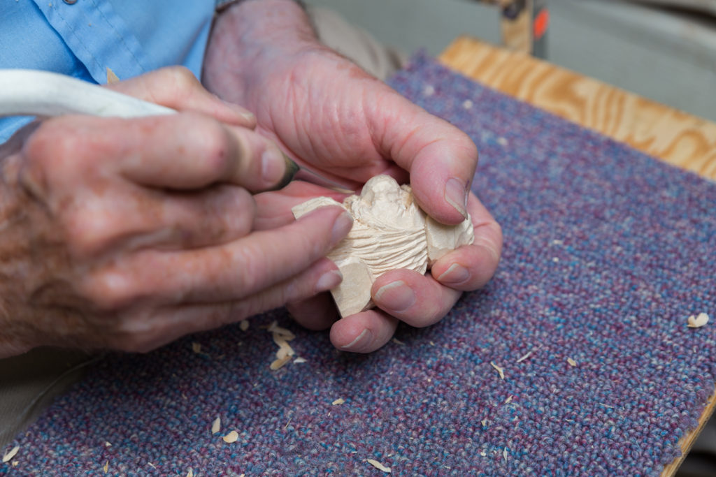 Close-up of hands carving wood in an activity room