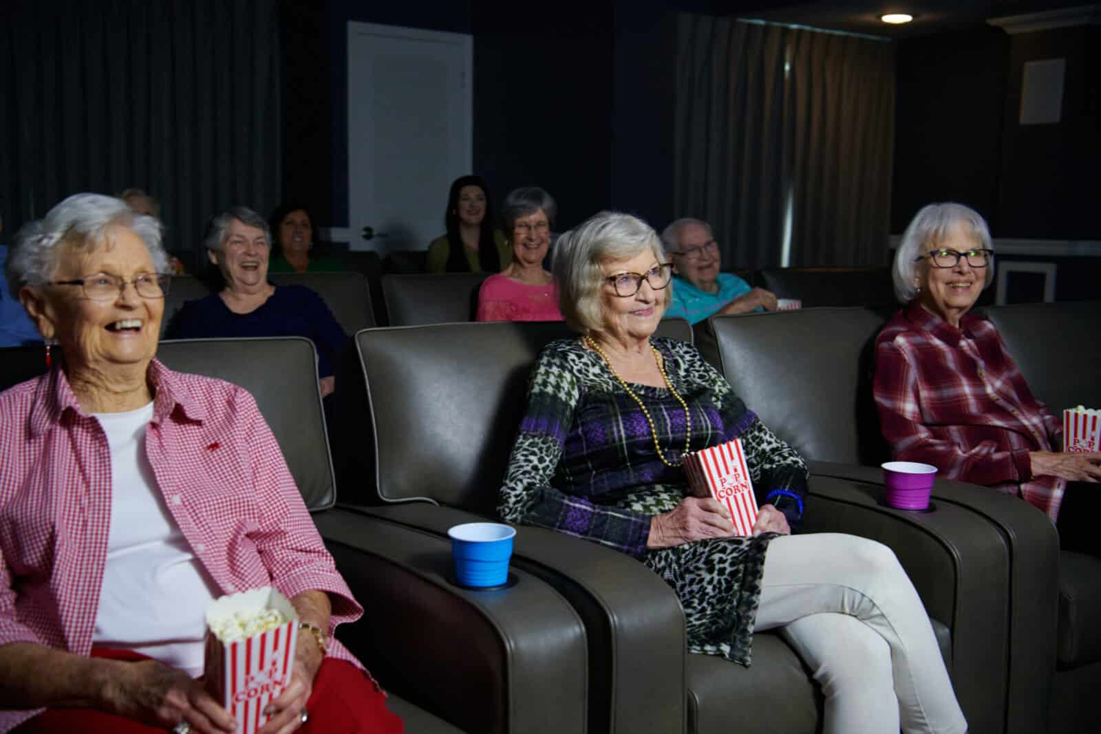 Residents enjoying a movie with popcorn in an activity room