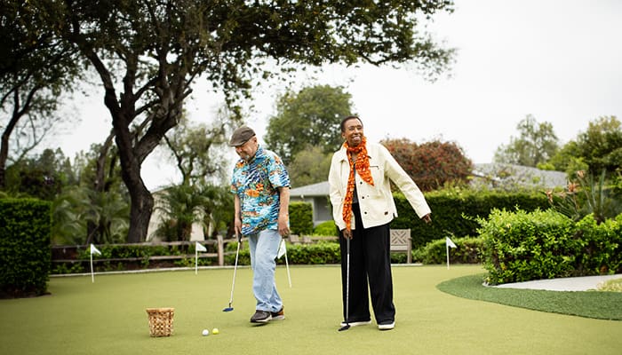 Residents enjoying outdoor mini-golf on a sunny day