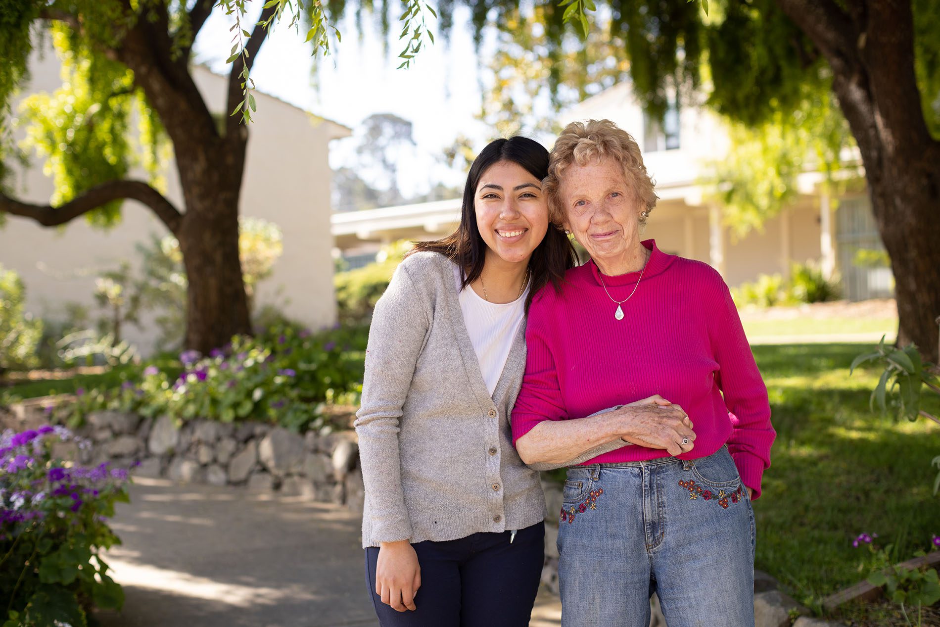 A smiling caregiver with a resident in a garden