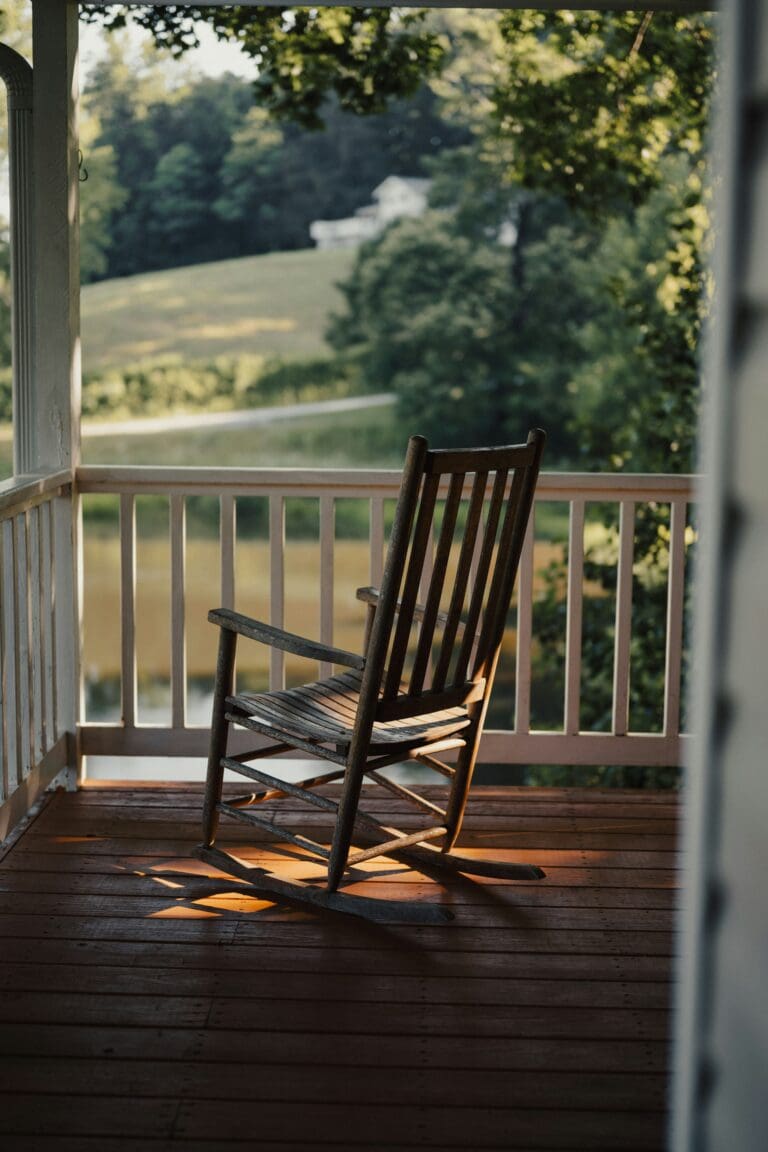 A rocking chair on a porch with a view of a serene landscape