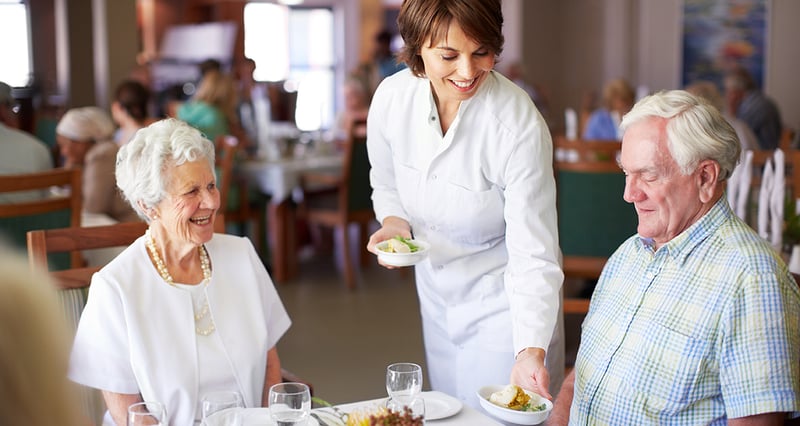 Staff serving food to residents in the dining room