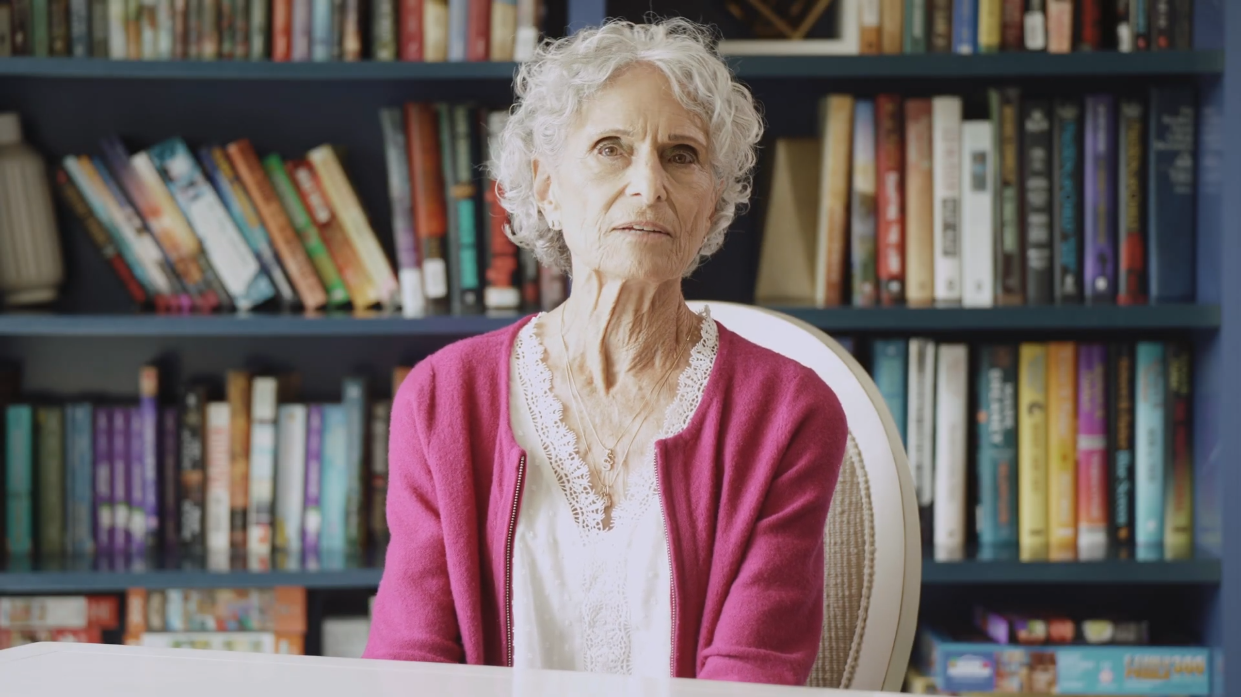 Resident seated in front of a bookshelf in a common area