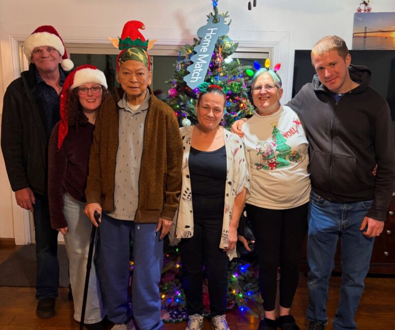Residents and staff posing together by a Christmas tree