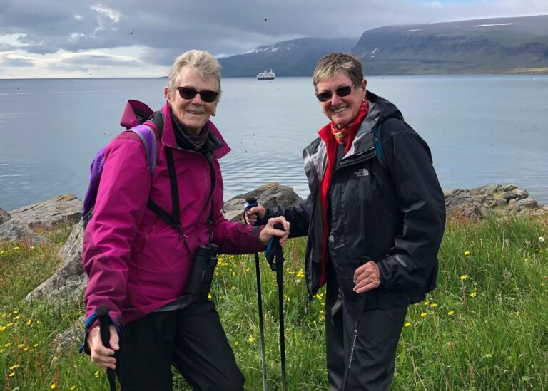 Two seniors enjoying an outdoor view with trekking poles
