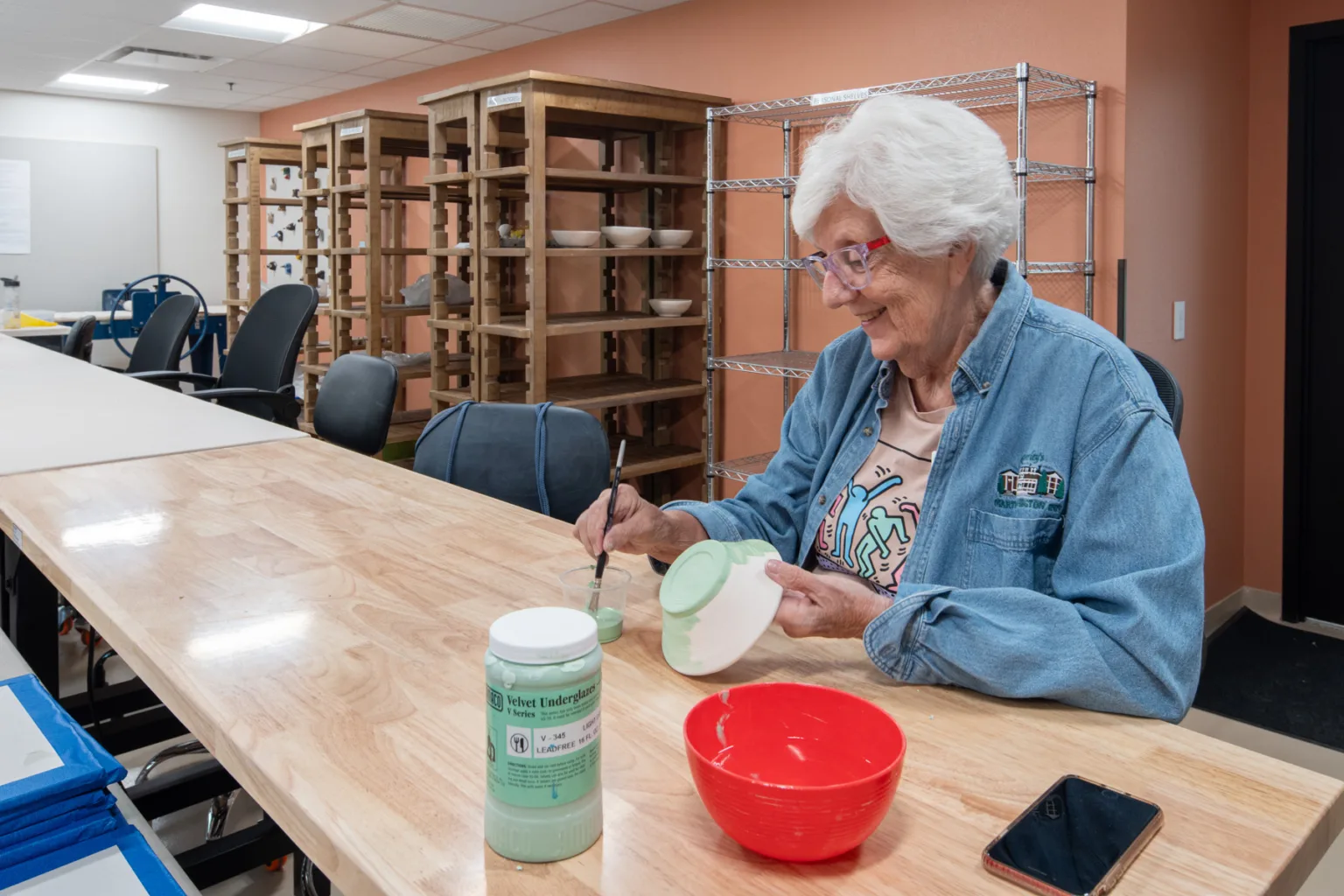 A resident painting pottery in an activity room