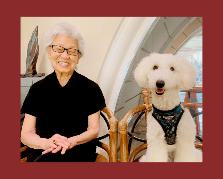 Resident smiling with a white dog in an indoor setting
