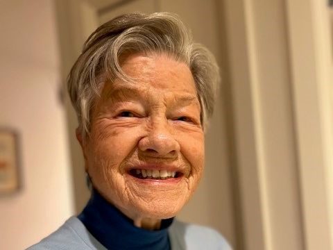 A smiling elderly woman in a bright setting