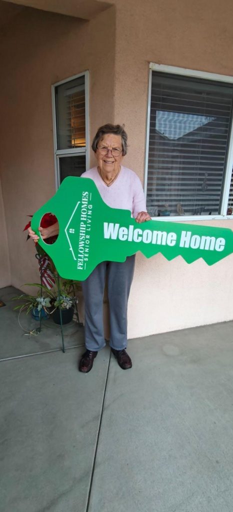 Resident holding a large key with 'Welcome Home' sign