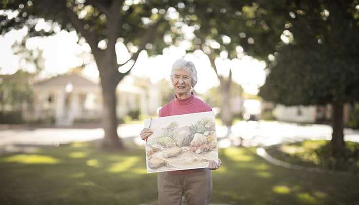 Resident holding a painting outdoors in a garden