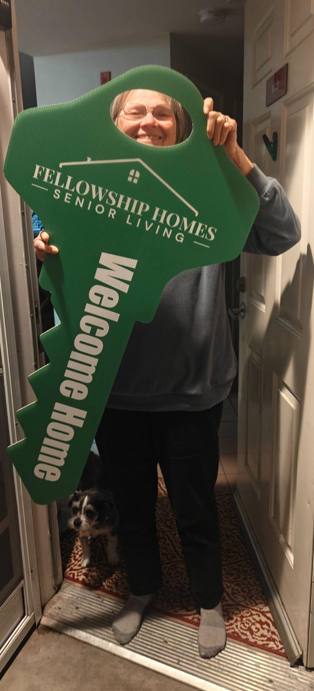 A resident holding a large welcome key inside the facility