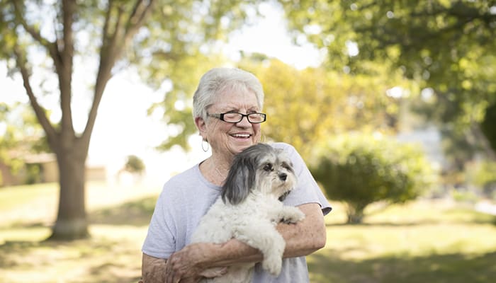 Resident smiling outdoors with a small dog