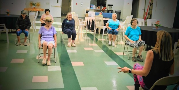 Residents participating in a seated exercise class in a common area