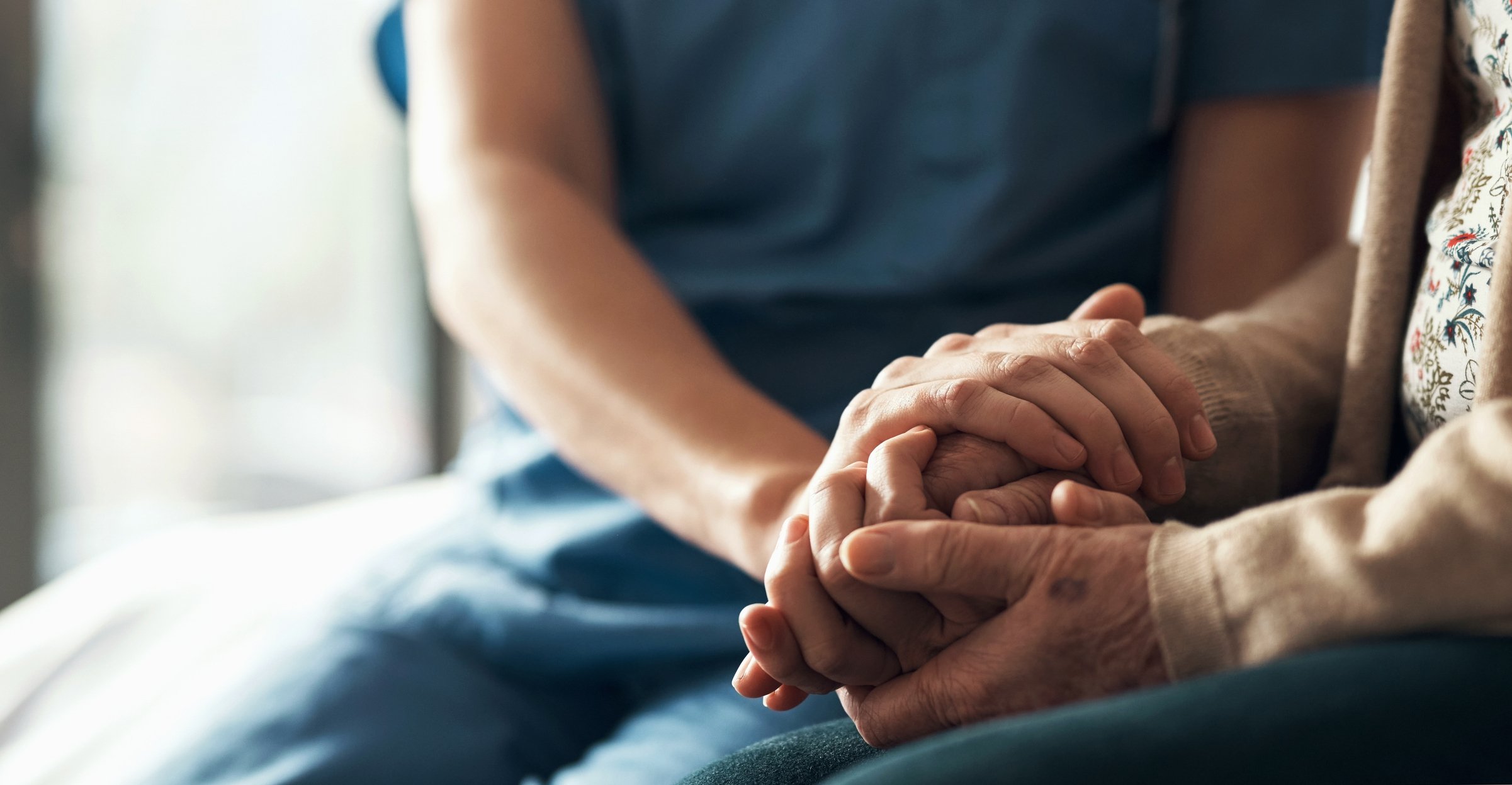 Close-up of a caregiver holding hands with a resident