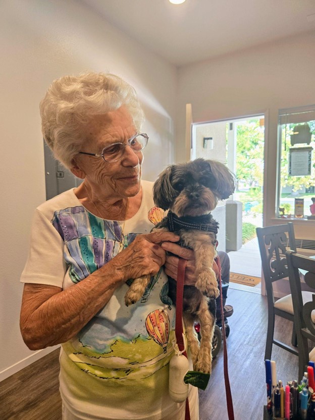 A resident lovingly holding a small dog indoors