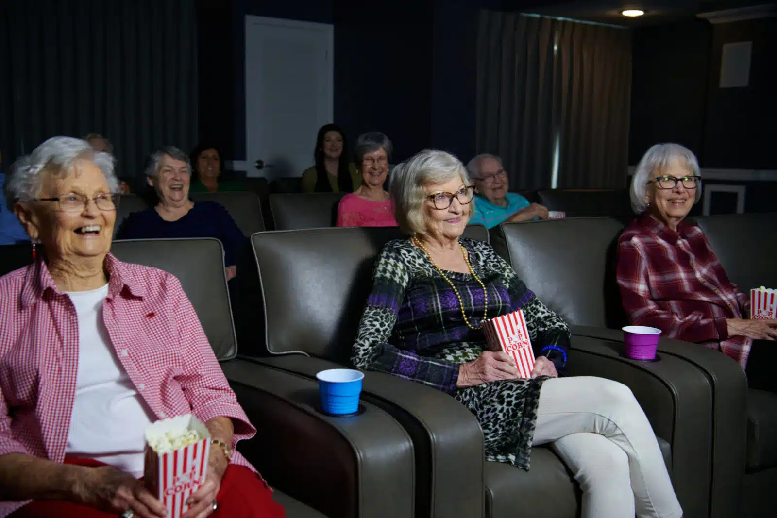 Residents enjoying a movie in a cozy cinema with popcorn