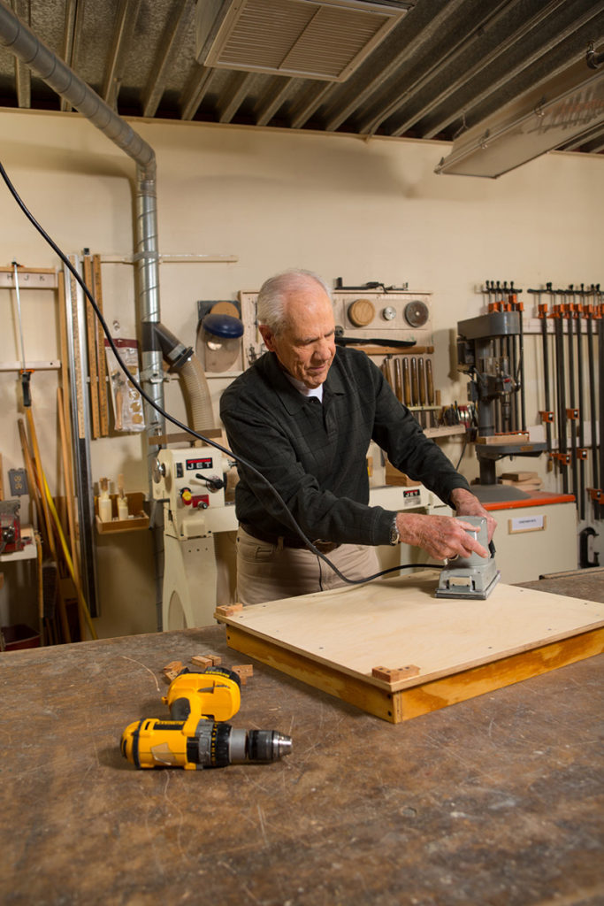 An elderly man working in a woodworking shop