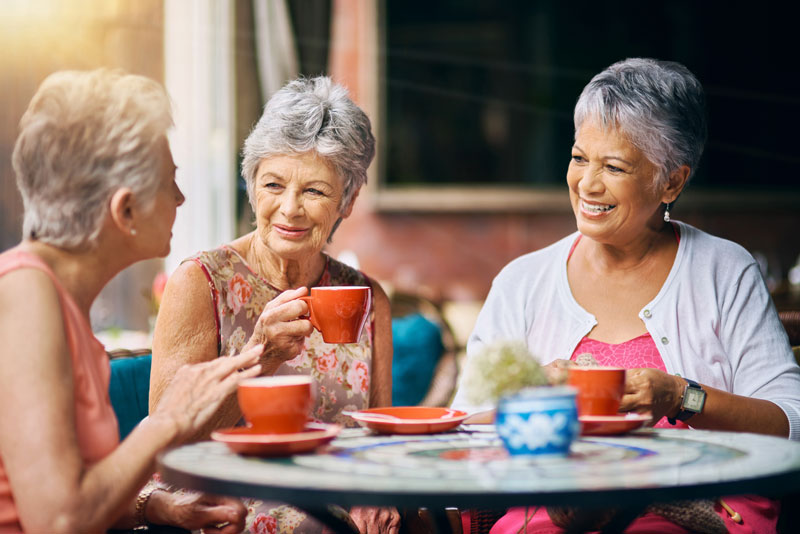 Three senior women enjoying coffee outdoors