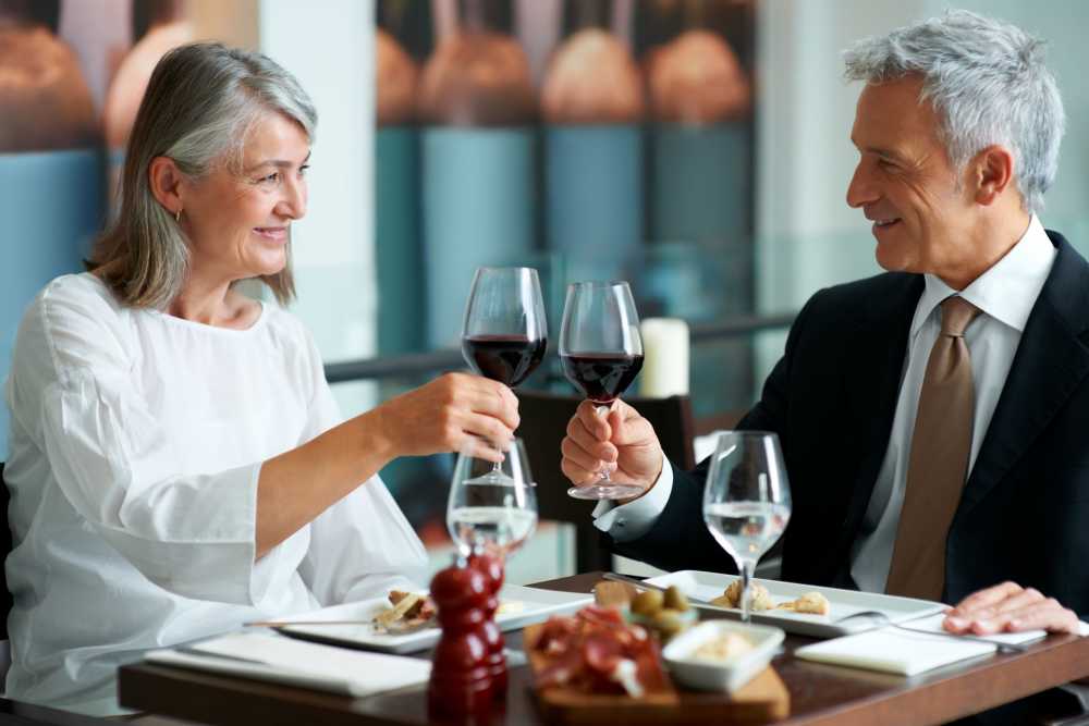 Two residents toasting with wine at a dining table.