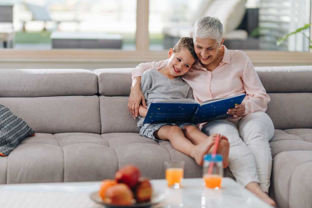 An older woman reading with a young child on a couch
