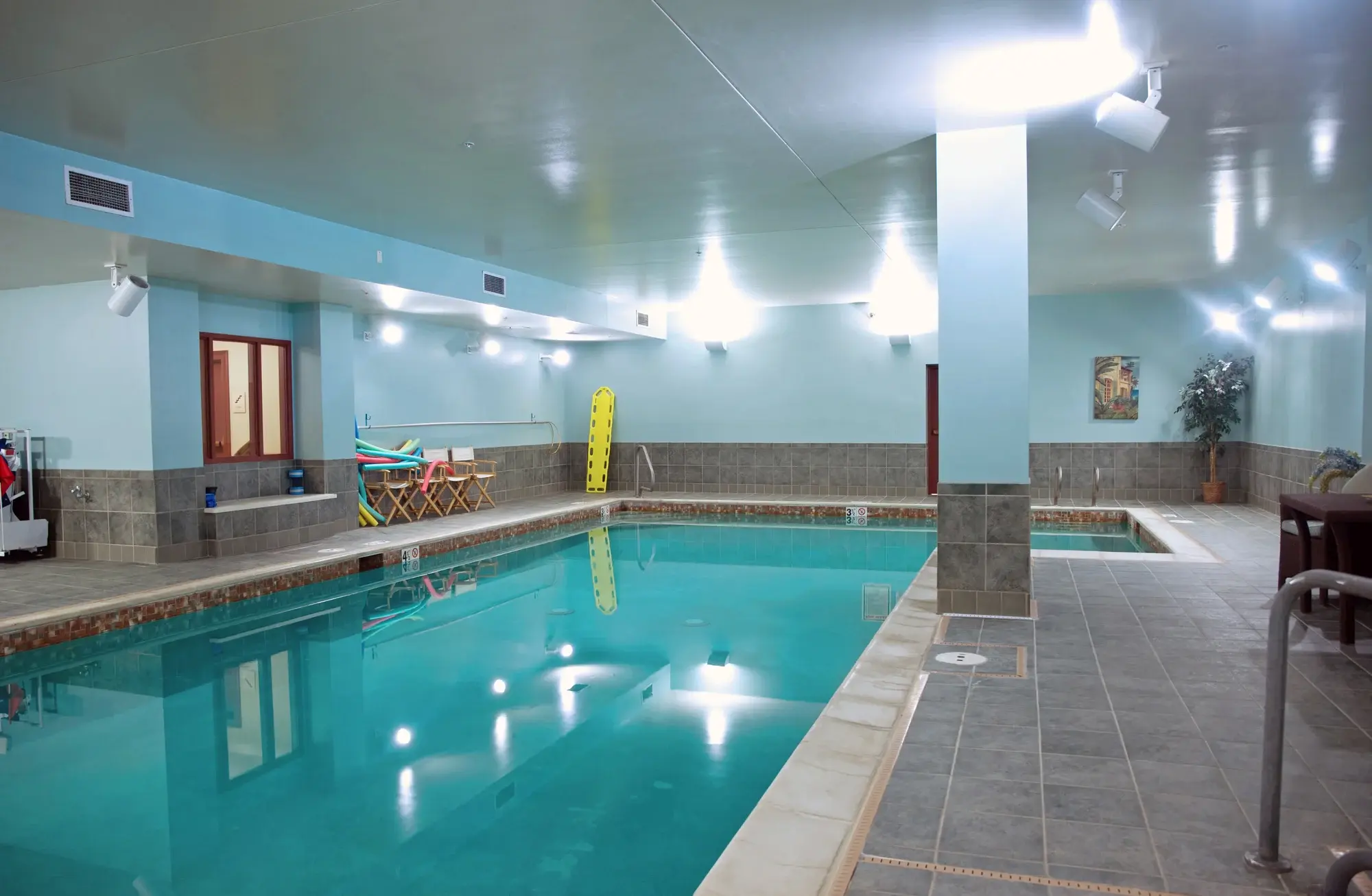 Indoor swimming pool area with seating and natural light