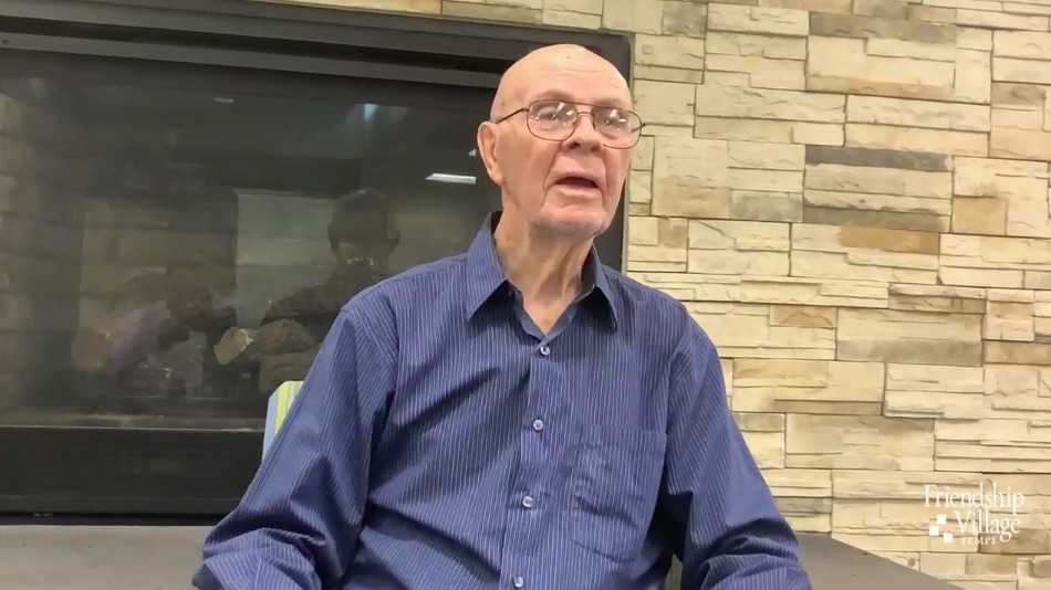 An elderly man sitting in front of a fireplace