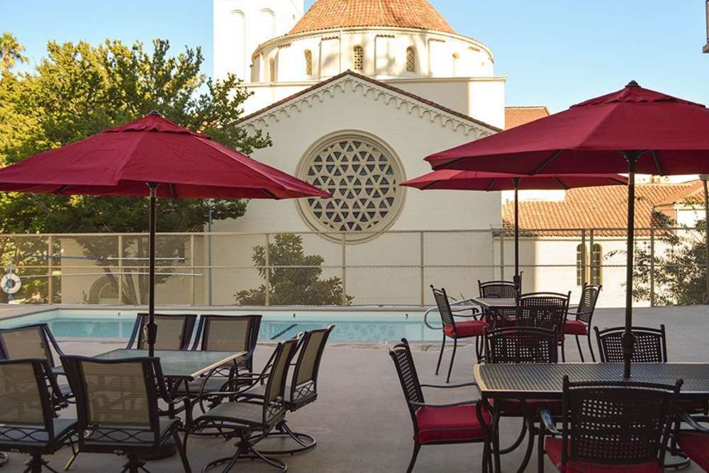 Outdoor seating area with red umbrellas and swimming pool
