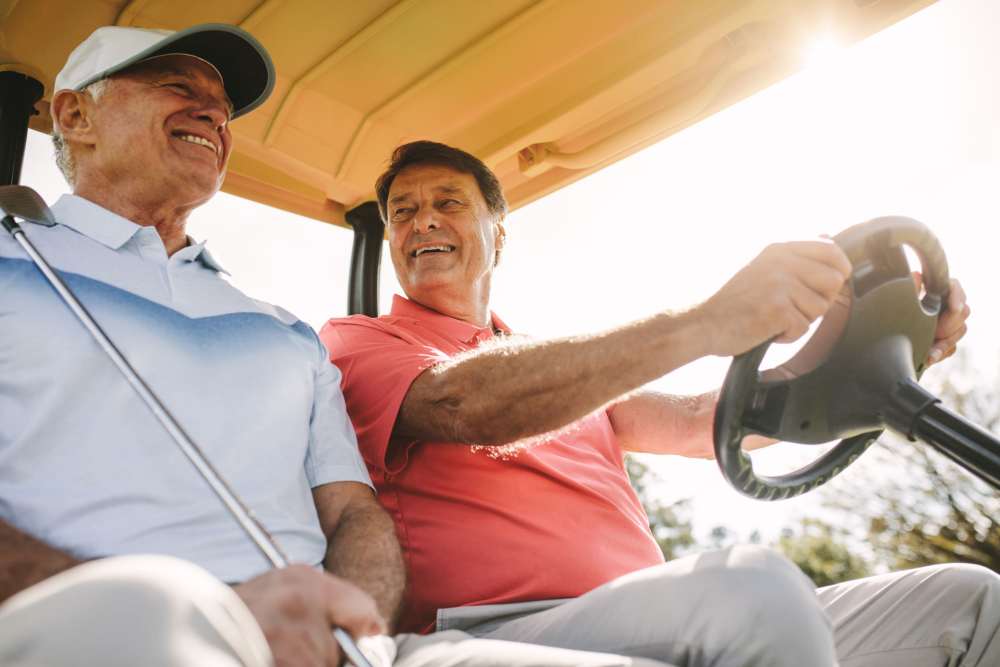 Two elderly men smiling in a golf cart