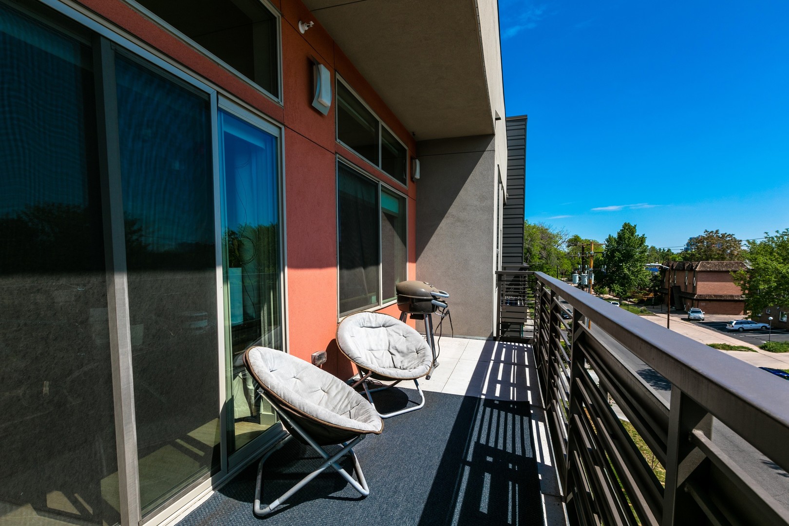 Balcony space with chairs and grill overlooking the outdoors