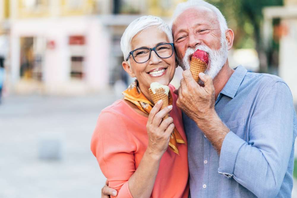 Happy seniors enjoying ice cream together in a park