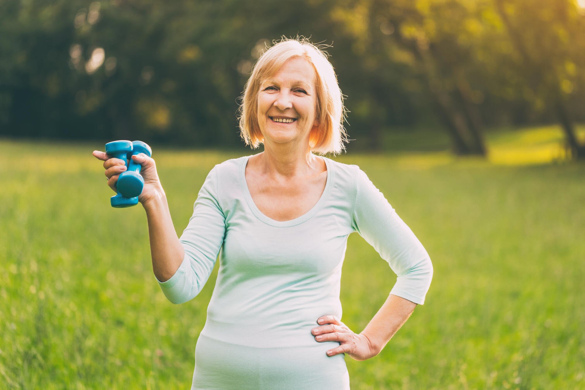 Senior woman exercising outdoors with dumbbell