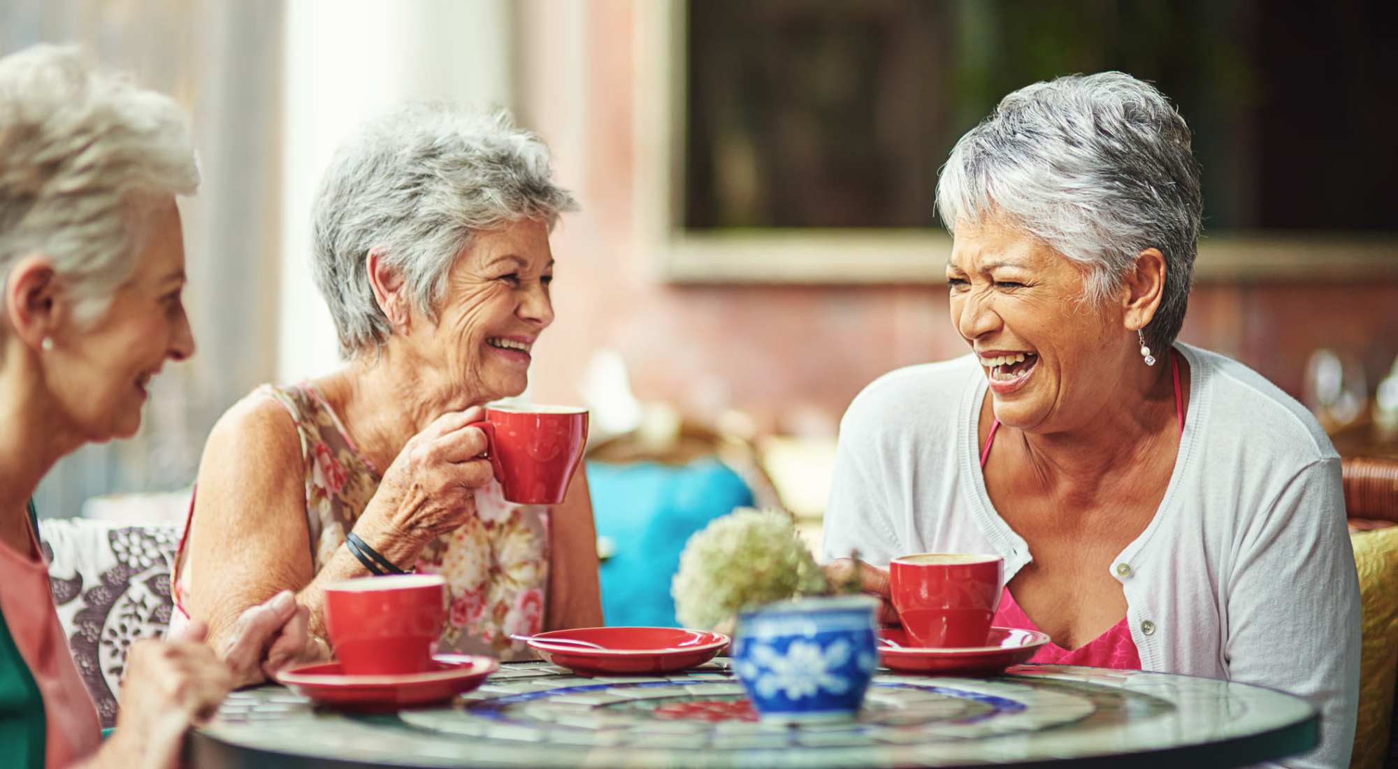 Three residents enjoying coffee and laughter together.